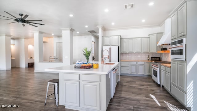 kitchen with white appliances, visible vents, light countertops, custom exhaust hood, and decorative columns