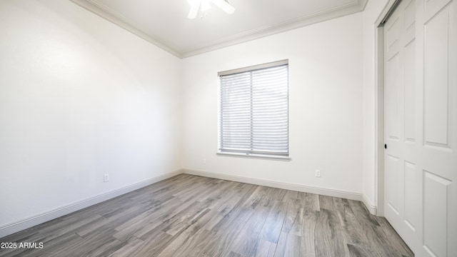 unfurnished bedroom with ornamental molding, a closet, baseboards, and wood finished floors