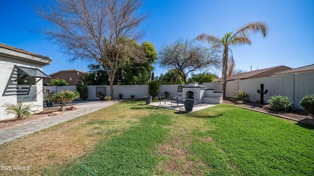 view of yard featuring a fenced backyard, an outdoor fireplace, and a patio