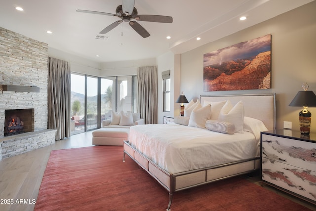 bedroom featuring a fireplace, dark wood-type flooring, ceiling fan, and access to exterior