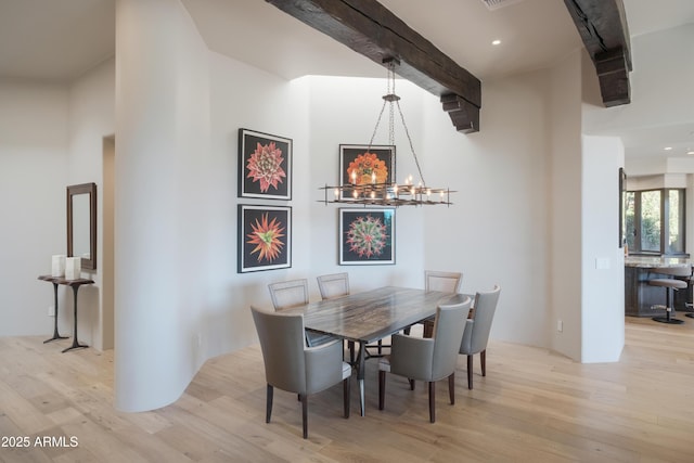 dining room featuring light wood-type flooring, beam ceiling, and a notable chandelier