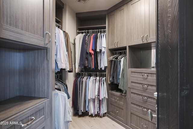 walk in closet with light hardwood / wood-style floors