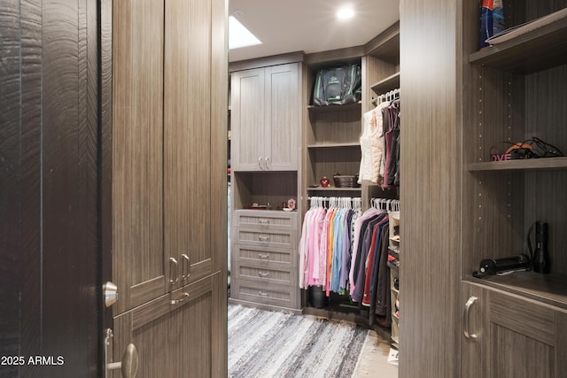 walk in closet with light hardwood / wood-style flooring