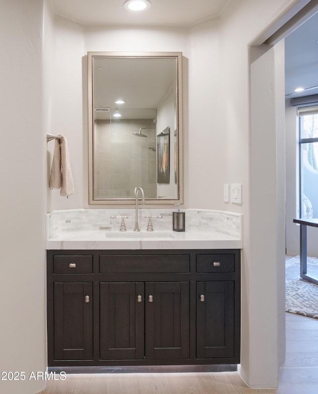 bathroom featuring tasteful backsplash, walk in shower, vanity, and hardwood / wood-style flooring