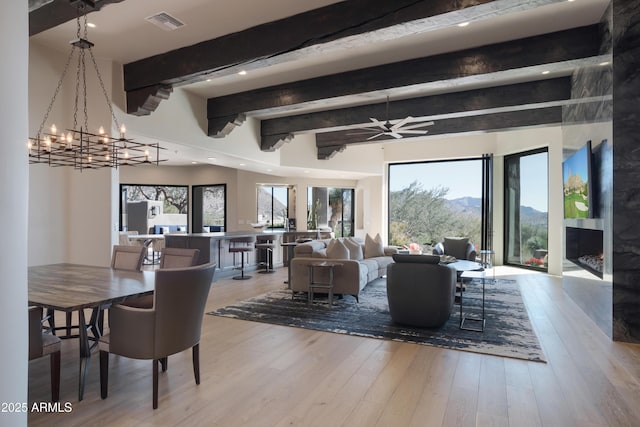 living room featuring light hardwood / wood-style floors, a healthy amount of sunlight, beamed ceiling, and a mountain view