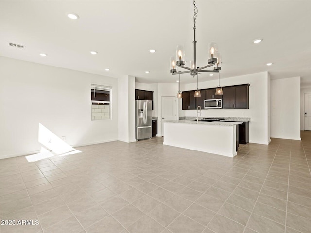 kitchen with light stone counters, stainless steel appliances, recessed lighting, an inviting chandelier, and a sink