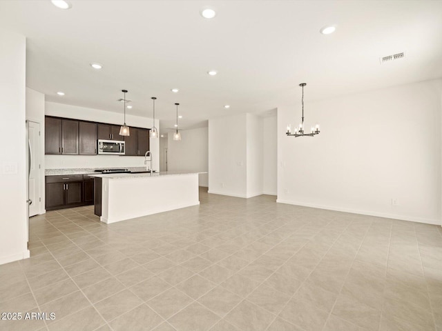 kitchen featuring open floor plan, stainless steel microwave, visible vents, and pendant lighting