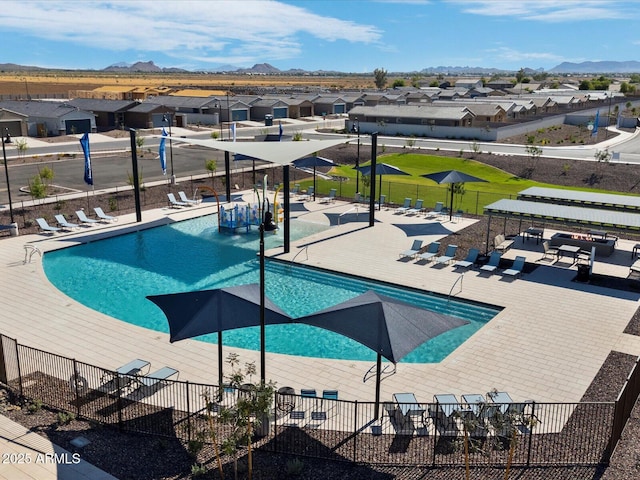 community pool with a patio area, a residential view, a mountain view, and fence