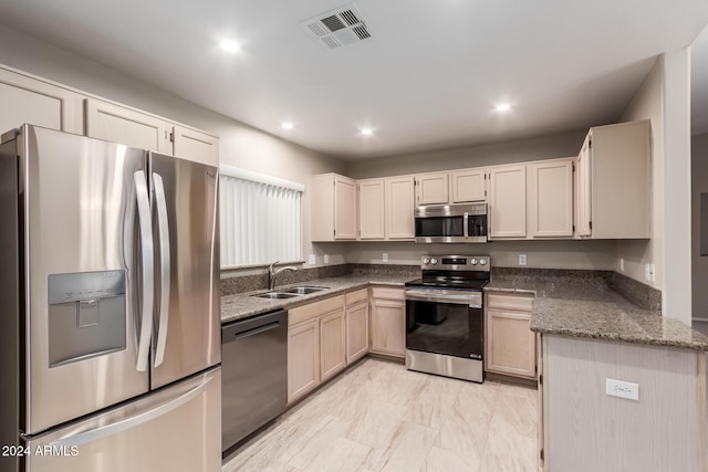 kitchen with stainless steel appliances, sink, and dark stone countertops