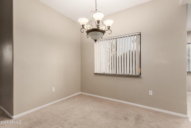 spare room with light carpet and an inviting chandelier