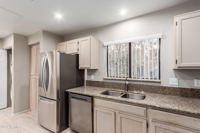 kitchen with appliances with stainless steel finishes, light stone countertops, and sink