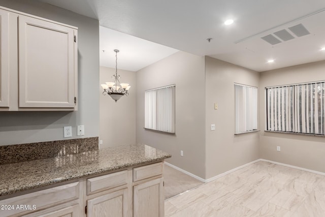 kitchen featuring a chandelier and light stone counters