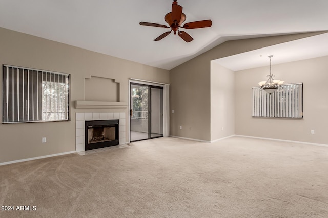 unfurnished living room with a tile fireplace, lofted ceiling, light colored carpet, and ceiling fan with notable chandelier