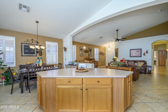 kitchen featuring visible vents, lofted ceiling, light countertops, arched walkways, and ceiling fan with notable chandelier