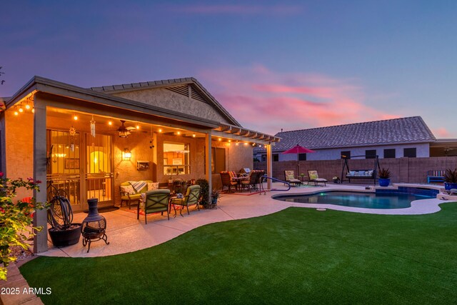 back of property at dusk with a patio area, a fenced in pool, a fenced backyard, a yard, and outdoor lounge area