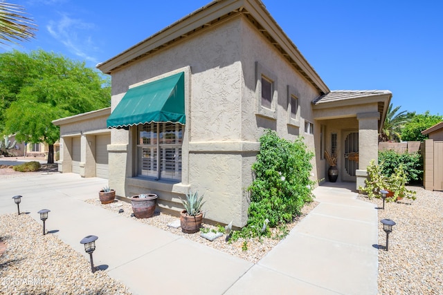 view of home's exterior with concrete driveway, fence, and stucco siding