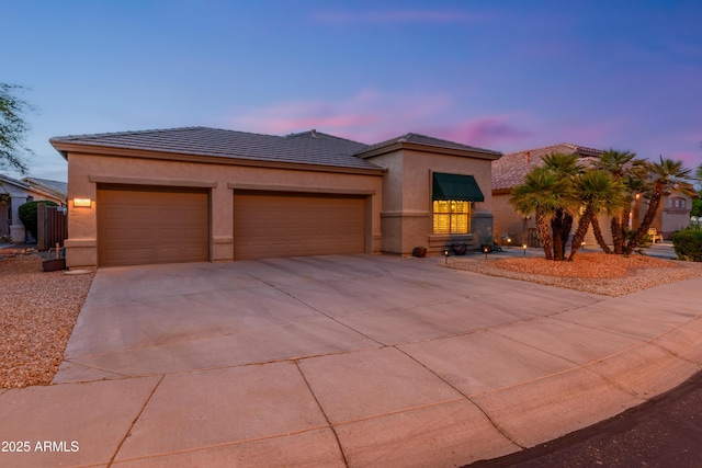 prairie-style house with an attached garage, stucco siding, driveway, and a tiled roof