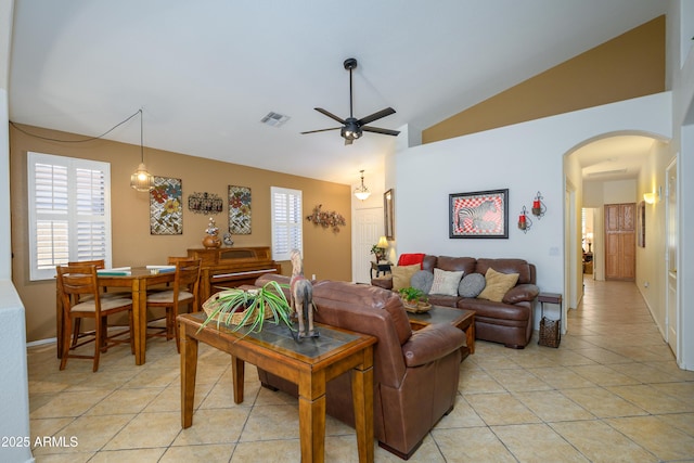 living area featuring light tile patterned flooring, arched walkways, high vaulted ceiling, a ceiling fan, and visible vents