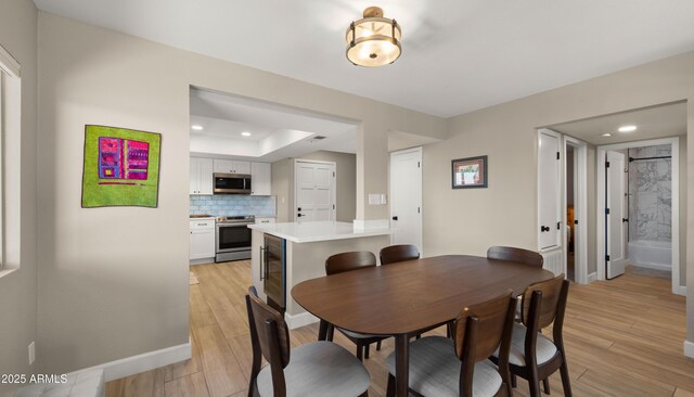 7424 N Via Camello Del Norte Unit 185, Scottsdale, AZ 85258 - dining room with recessed lighting, light wood-type flooring, baseboards, a raised ceiling, and wine cooler