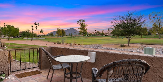 7424 N Via Camello Del Norte Unit 185, Scottsdale, AZ 85258 - patio terrace at dusk featuring view of golf course, a lawn, and a mountain view