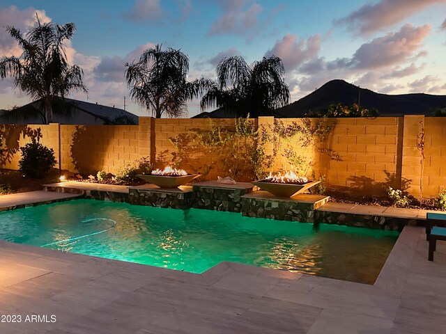 2308 E Dry Wood Rd, Phoenix, AZ 85024 - pool at dusk featuring a fire pit, a fenced backyard, and a patio