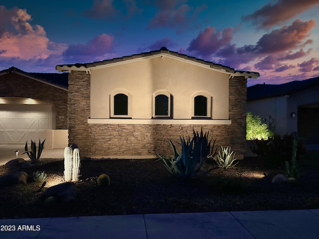 2308 E Dry Wood Rd, Phoenix, AZ 85024 - property exterior at dusk with stone siding, stucco siding, and an attached garage