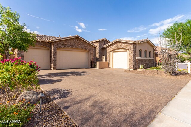 2308 E Dry Wood Rd, Phoenix, AZ 85024 - mediterranean / spanish-style home featuring an attached garage, a tile roof, driveway, stucco siding, and stone siding