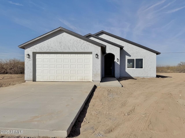 ranch-style home featuring stucco siding, an attached garage, and concrete driveway