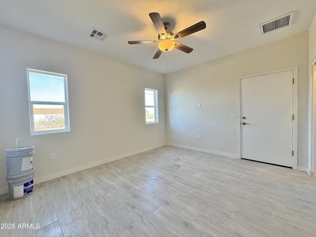 empty room with light wood finished floors, visible vents, and baseboards