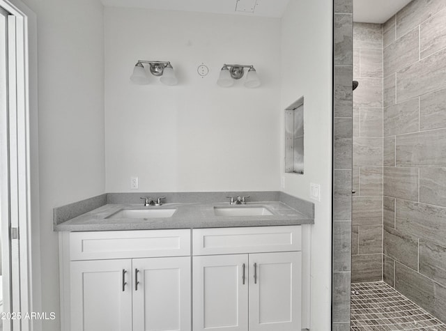 bathroom with a sink, double vanity, and a tile shower