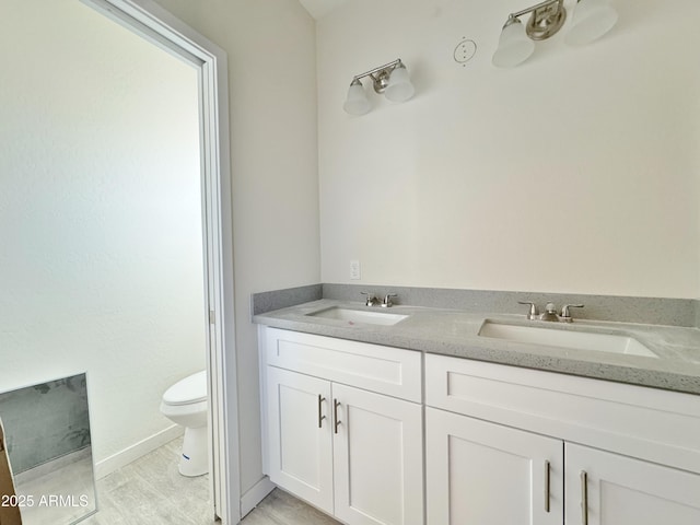 full bathroom with double vanity, toilet, and a sink