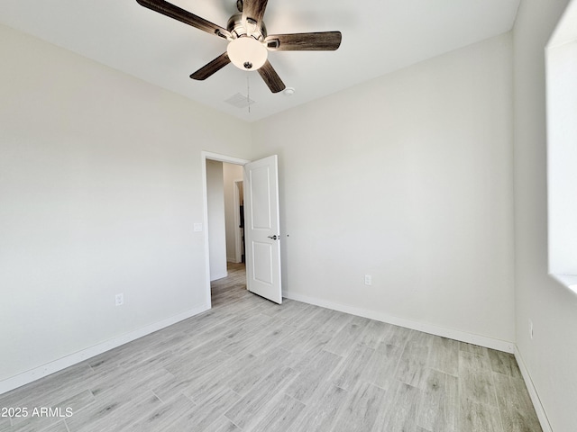 spare room with a ceiling fan, visible vents, light wood-style floors, and baseboards