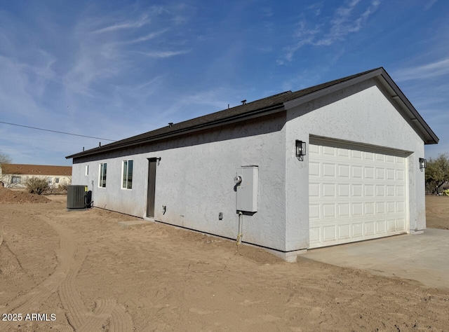 view of property exterior featuring stucco siding, a garage, and central AC unit