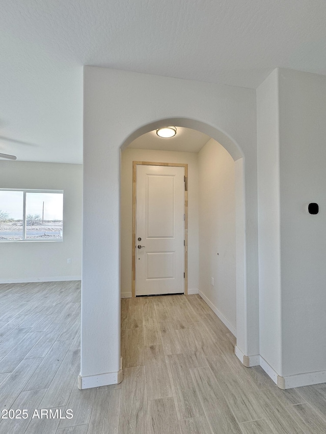 entryway with arched walkways, baseboards, and wood finished floors