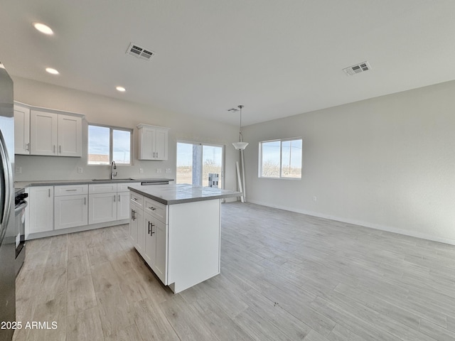 kitchen featuring light wood finished floors, visible vents, white cabinetry, and a center island