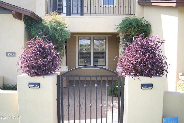 15387 W Columbine Dr, Surprise, AZ 85379 - view of exterior entry with a gate, a balcony, stucco siding, and fence