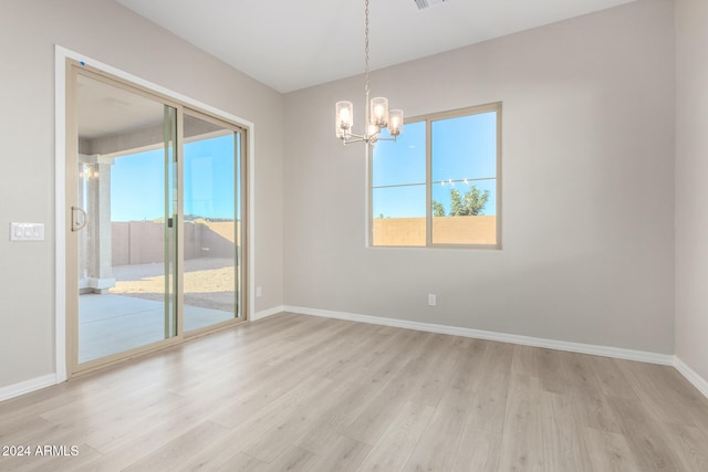 empty room featuring light wood-type flooring and an inviting chandelier