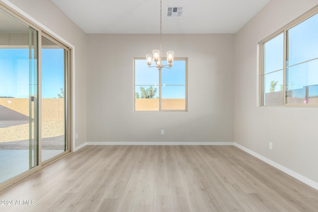 empty room with light hardwood / wood-style floors and a notable chandelier