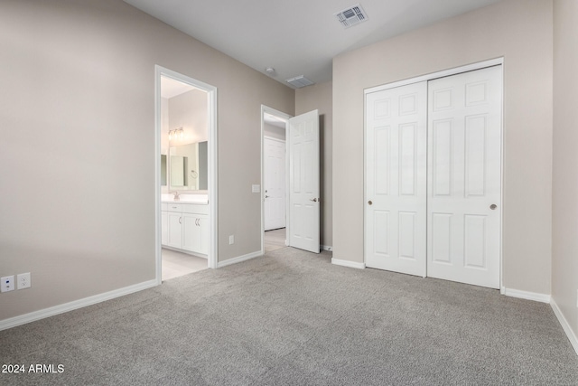 unfurnished bedroom with ensuite bathroom, light colored carpet, and a closet