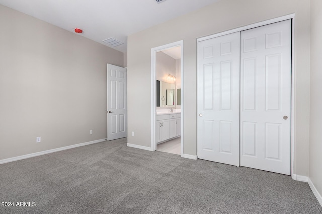 unfurnished bedroom featuring light colored carpet, ensuite bath, and a closet