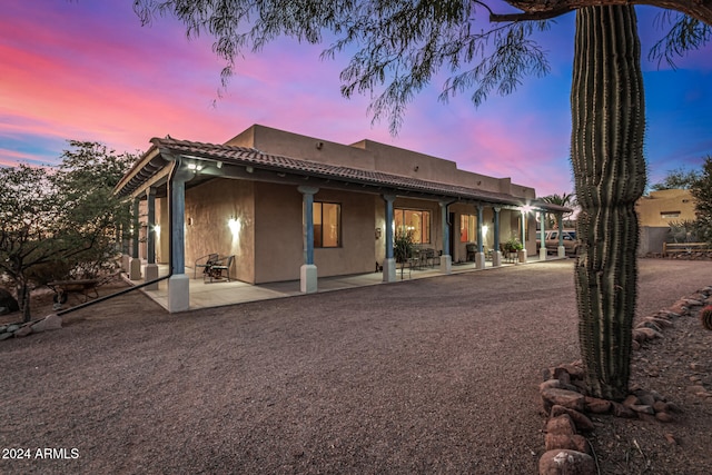 back house at dusk featuring a patio