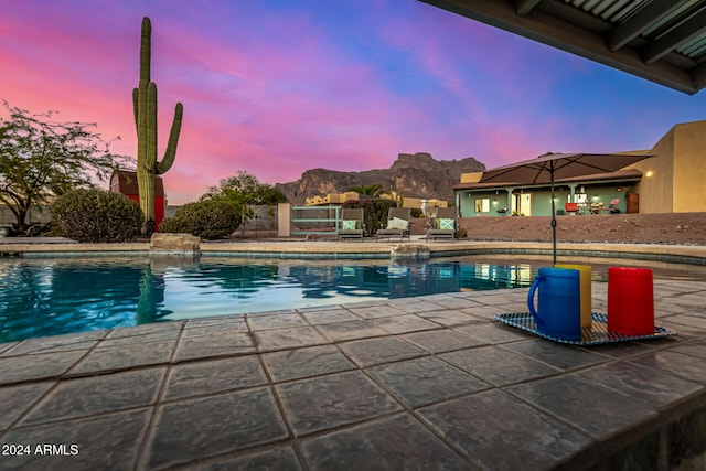 pool at dusk with a mountain view and a patio area