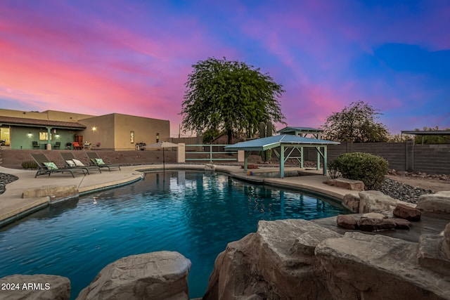 pool at dusk with a gazebo and a patio