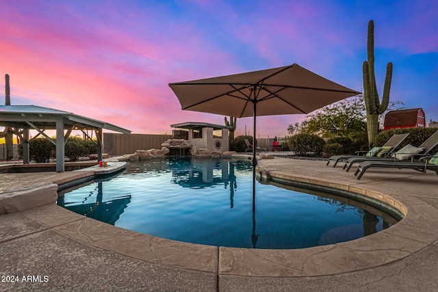 pool at dusk with a gazebo and a patio area