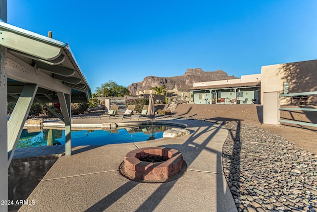 view of pool with a fire pit, a mountain view, and a patio