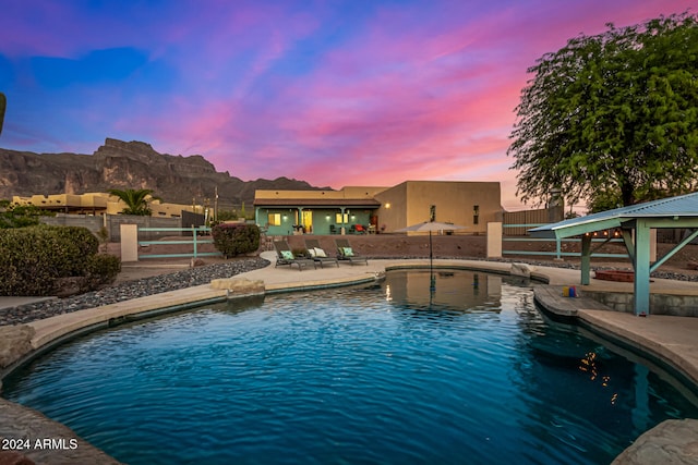 pool at dusk featuring a gazebo, a mountain view, and a patio