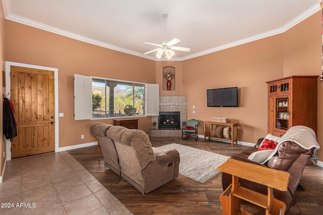 living room featuring tile patterned floors, ceiling fan, crown molding, and a tiled fireplace