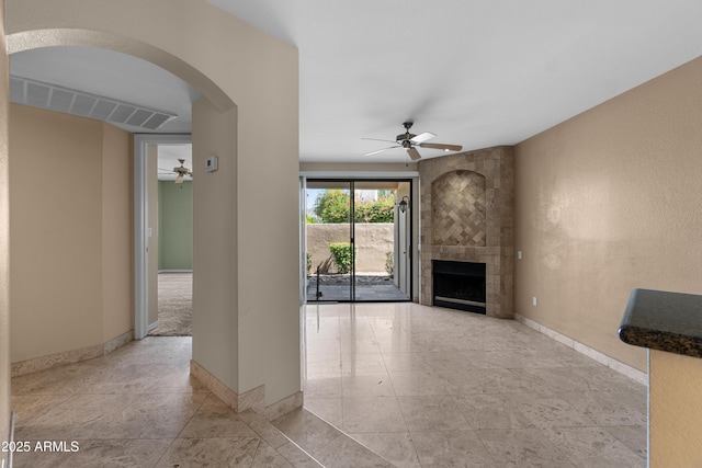 3235 E Camelback Rd Unit 124, Phoenix, AZ 85018 - unfurnished living room with ceiling fan, arched walkways, baseboards, and a large fireplace