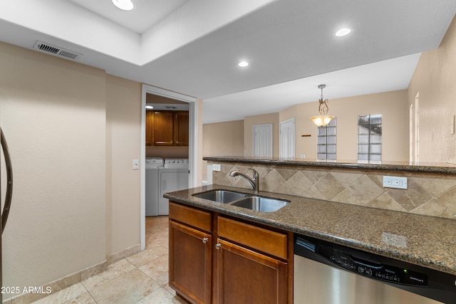 3235 E Camelback Rd Unit 124, Phoenix, AZ 85018 - kitchen featuring stainless steel dishwasher, separate washer and dryer, a sink, tasteful backsplash, and dark stone counters