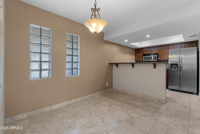 3235 E Camelback Rd Unit 124, Phoenix, AZ 85018 - kitchen featuring stainless steel appliances, dark countertops, baseboards, a peninsula, and a breakfast bar area